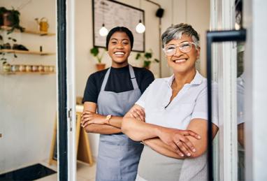 Female server and small business owner standing together in a café smiling
