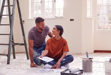 couple sitting on floor with paint chart ready to decorate new home