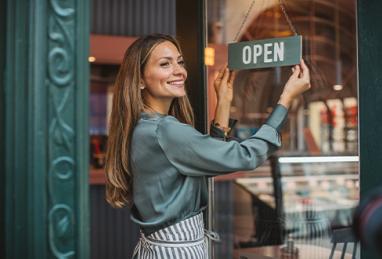 Young woman owner of ice cream shop in town opening her store and waiting for customers