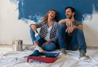 happy young couple laughing while painting their house